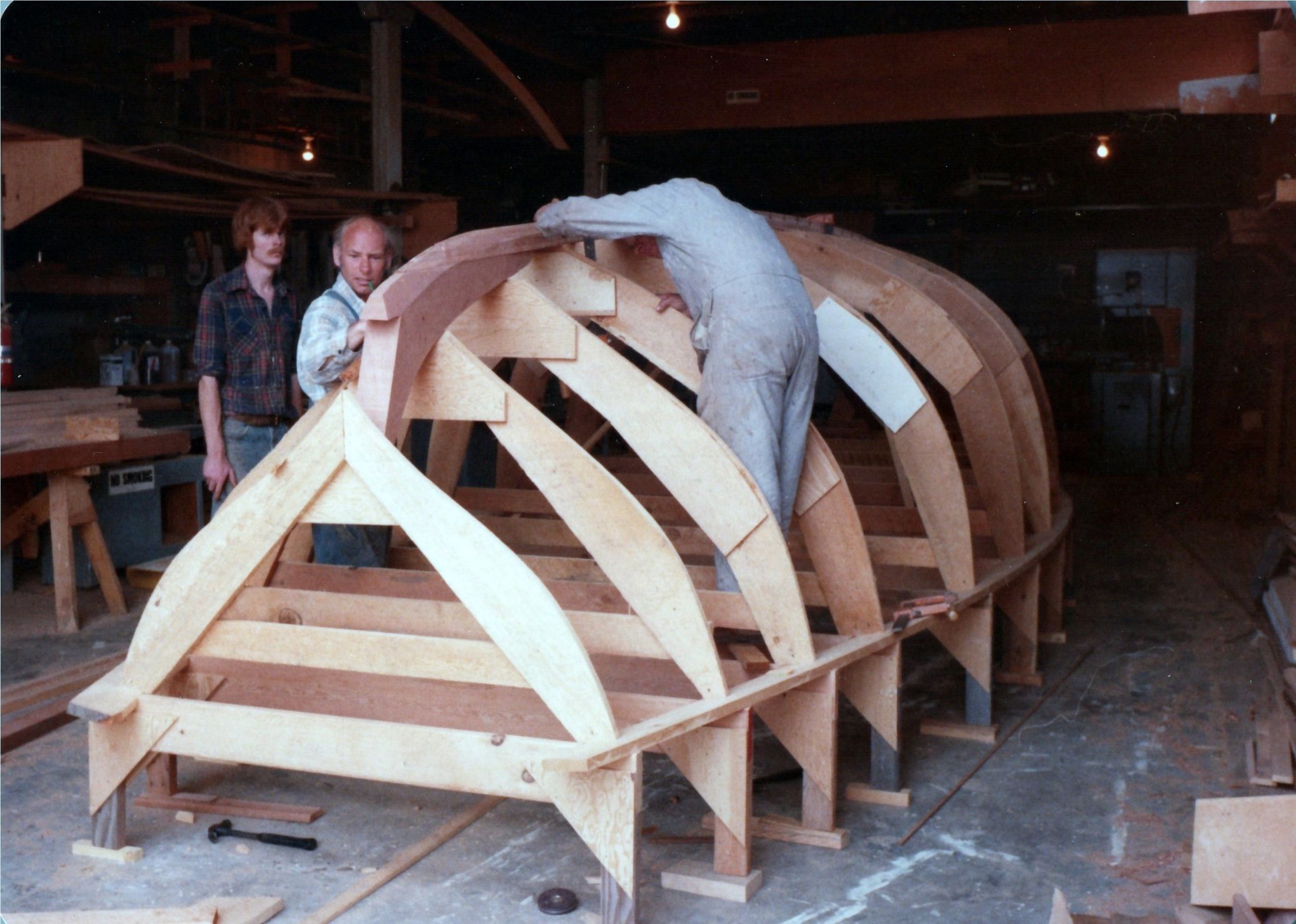 Three men at the molds, one leaning over the top of the jig