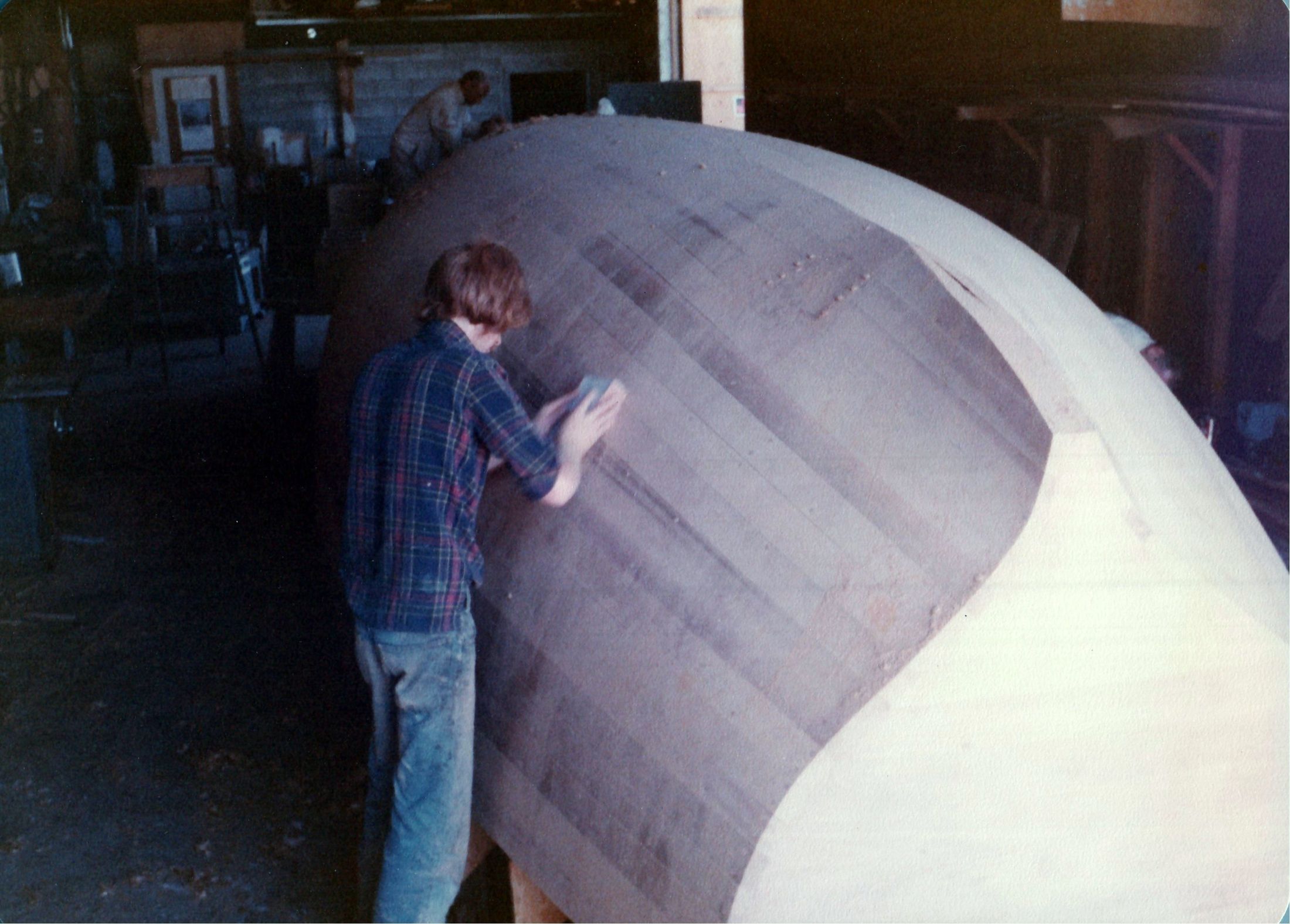 A man fairing the hull by hand