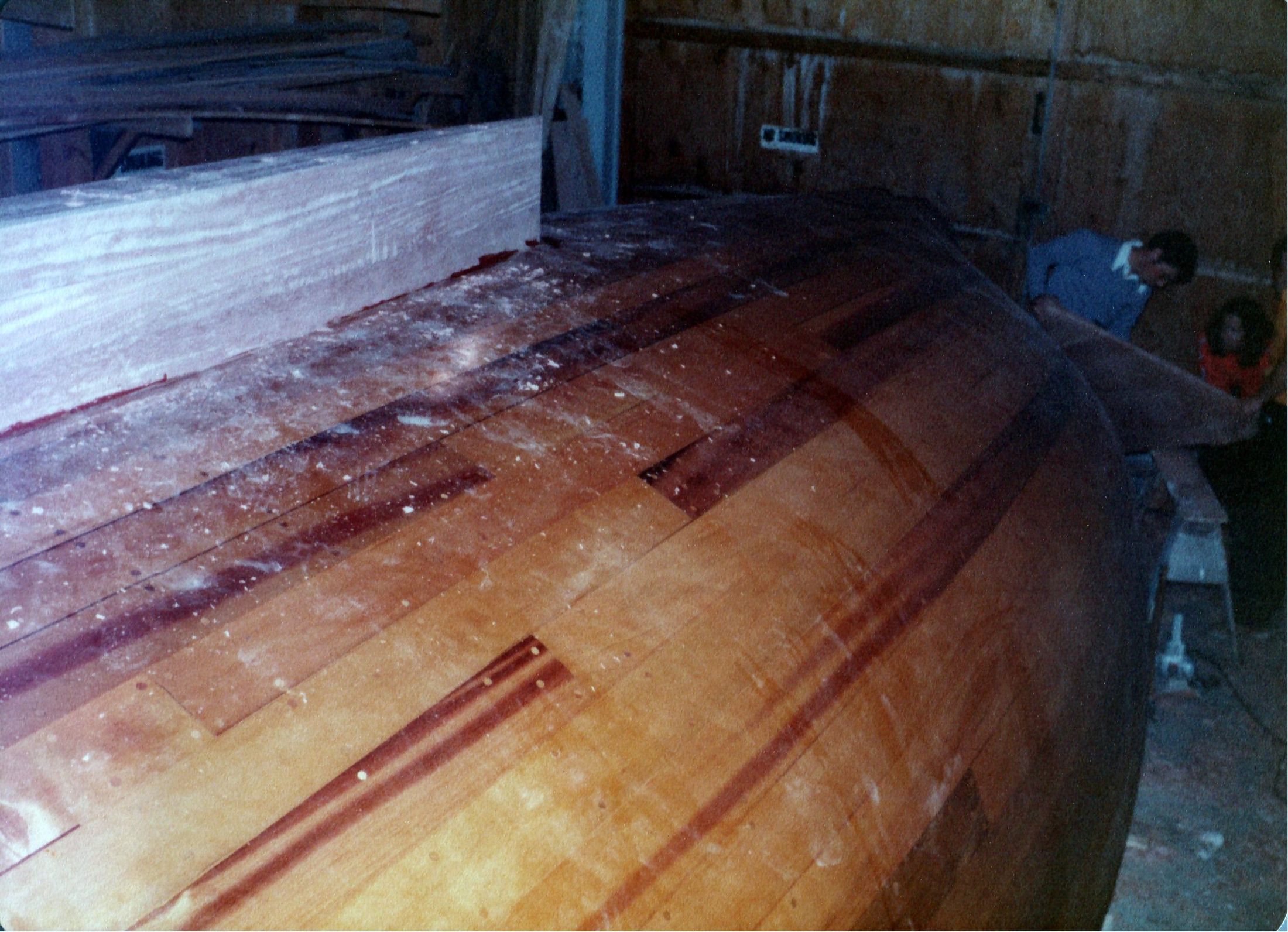 The hull turned right way up, the planking bright under the lamps